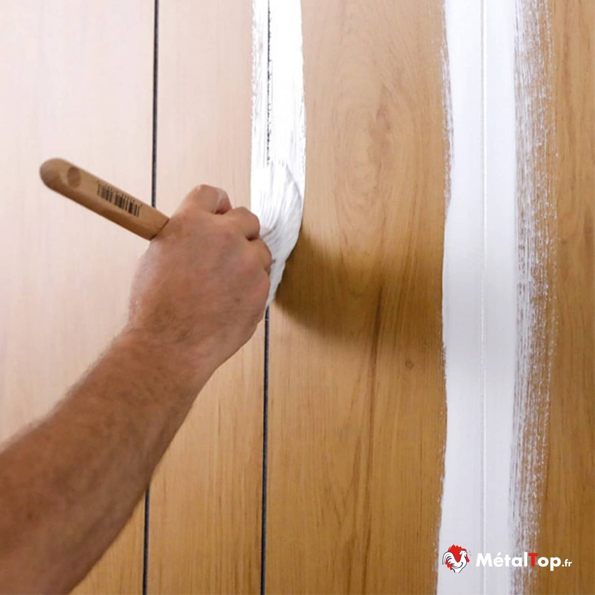Application de peinture blanche au pinceau sur des lambris en bois clair