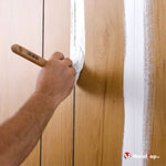 Application de peinture blanche au pinceau sur des lambris en bois clair