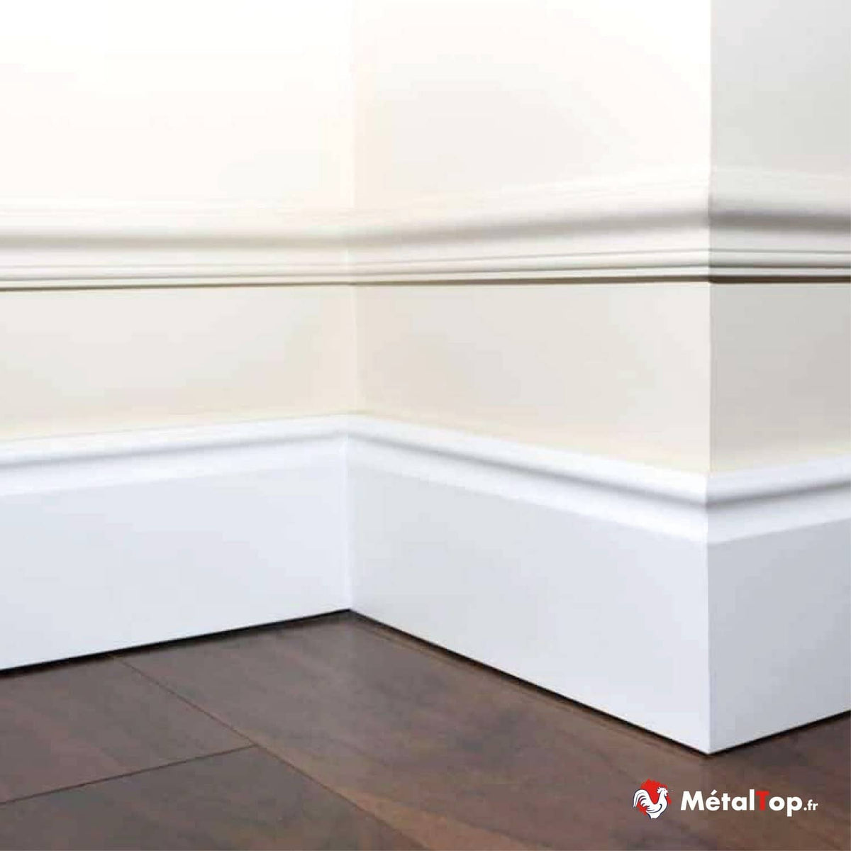 Plinthe et moulure blanches dans un angle de pièce, posées sur un parquet en bois brun