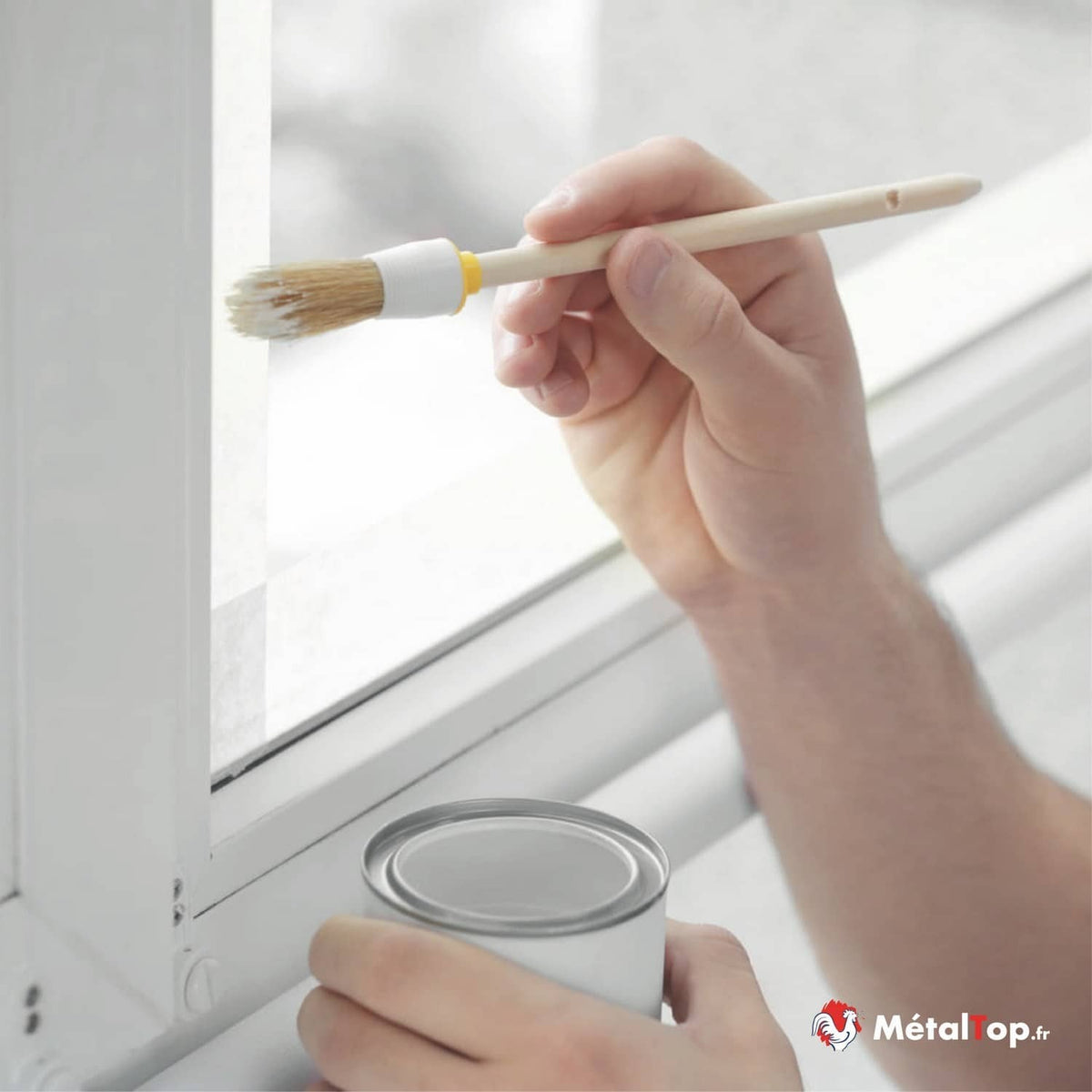 Application de peinture blanche au pinceau sur le cadre d'une fenêtre blanche