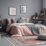 Chambre aux murs gris, lit avec linge rose, coussins et plaid en maille grise, tapis motifs roses