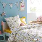 Parure de lit blanche à fleurs jaunes et papillons dans une chambre d'enfant aux murs bleus