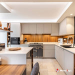 Cuisine moderne aux façades beige, crédence en bois, cuisinière anthracite et îlot central