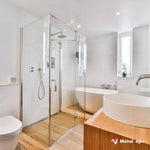 Salle de bain moderne avec douche en verre, baignoire blanche et vasques sur meuble en bois