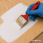 Application de peinture blanche au pinceau sur un panneau de bois clair