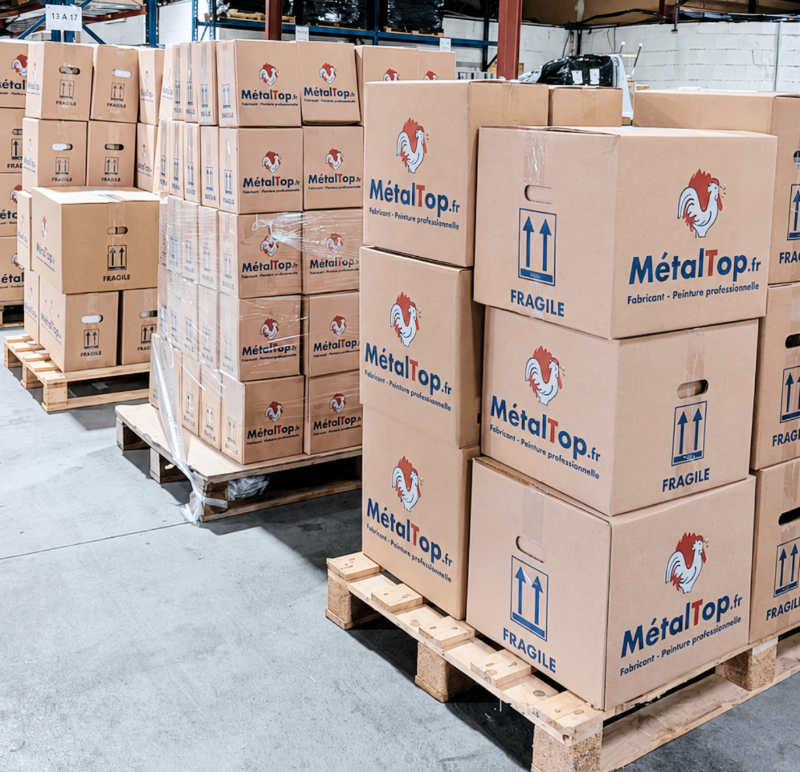 Cartons MétalTop empilés sur palettes en entrepôt, marqués FRAGILE