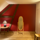 Pièce intérieure aux murs rouges avec miroir ovale doré, photo client