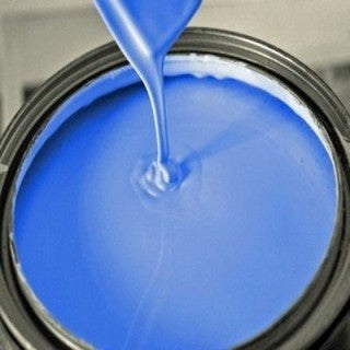 Peinture bleue vive coulant dans un pot de peinture métallique ouvert