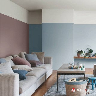 Salon aux murs peints en blocs bordeaux, bleu et blanc, avec canapé beige et coussins colorés