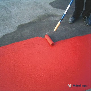 Application de peinture rouge au rouleau sur un sol gris en béton